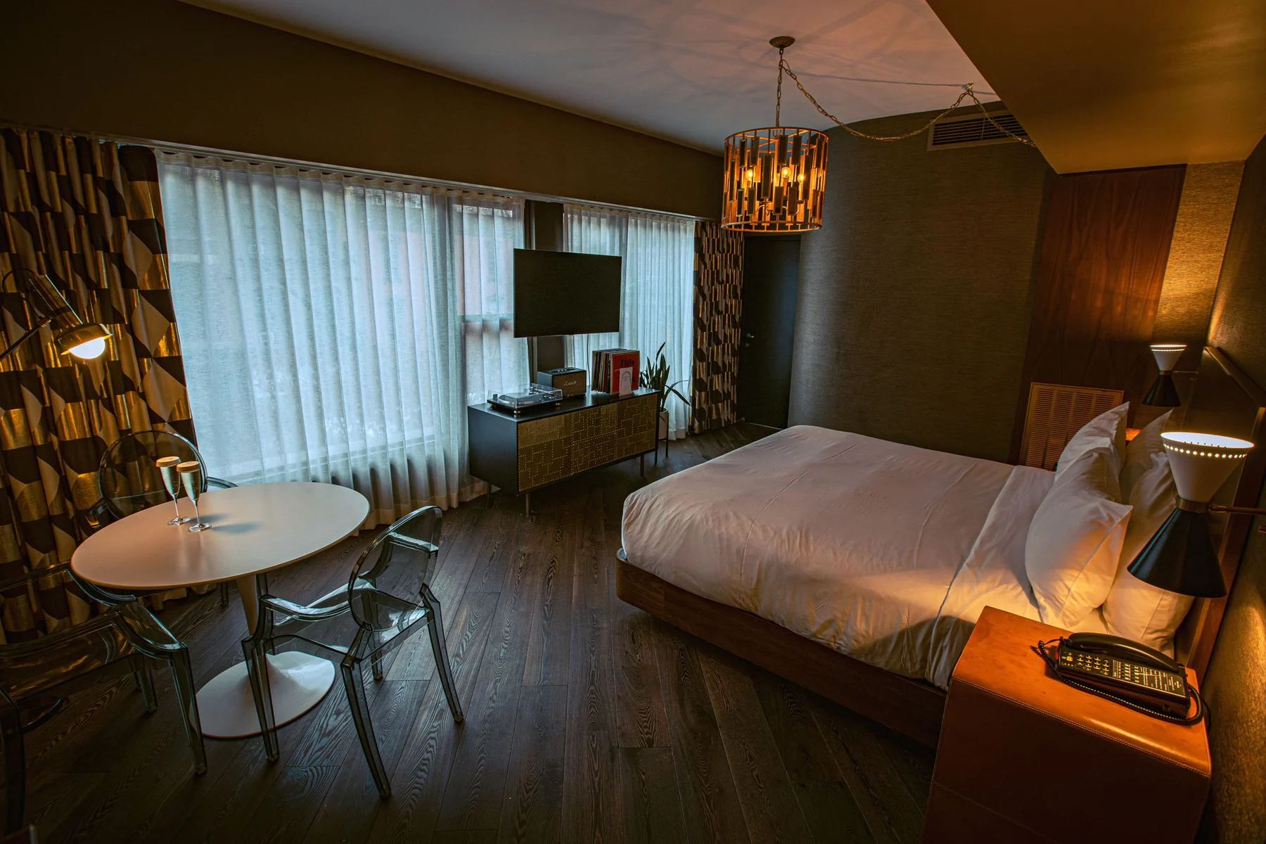A real Manhattan hotel guestroom with a neatly made bed, warm wood furnishings and city-facing windows